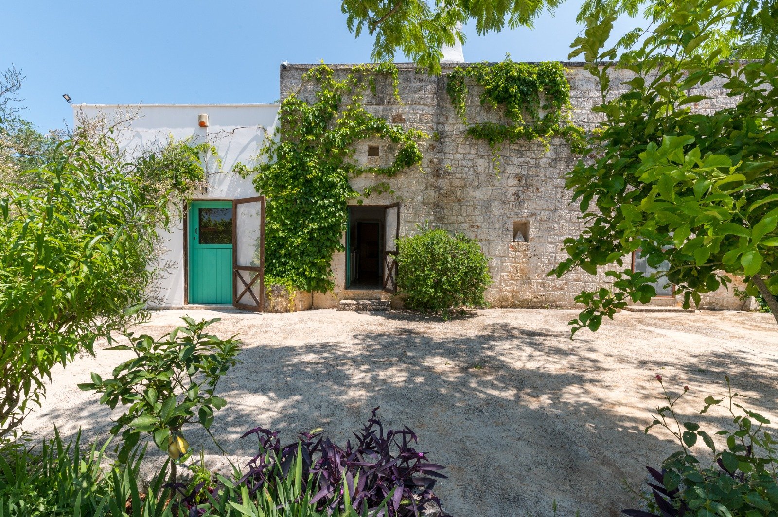Cortile in pietra con porta verde della Masseria Bel Cortile