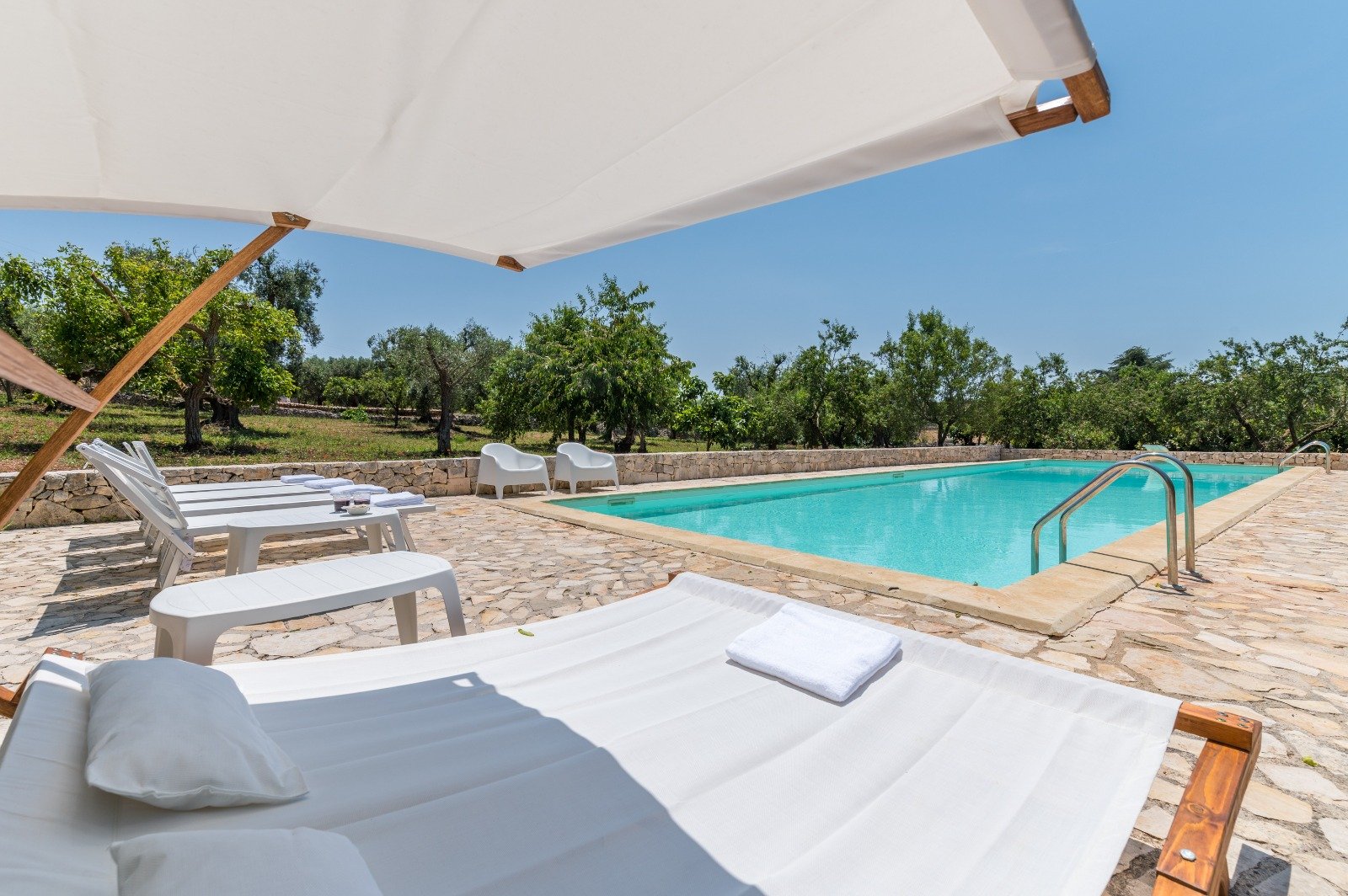 Piscina con lettini e ombrellone alla Masseria Bel Cortile